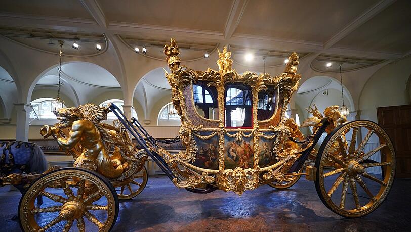 Die goldene Staatskutsche steht in den Royal Mews (Stallungen) im Buckingham Palace ausgestellt. König Charles III. und seine Königsgemahlin werden in der Diamond Jubilee State Coach, eine geschlossene Kutsche mit sechs Pferden, am 6. Mai 2023 zu den Feierlichkeiten der Krönung fahren.