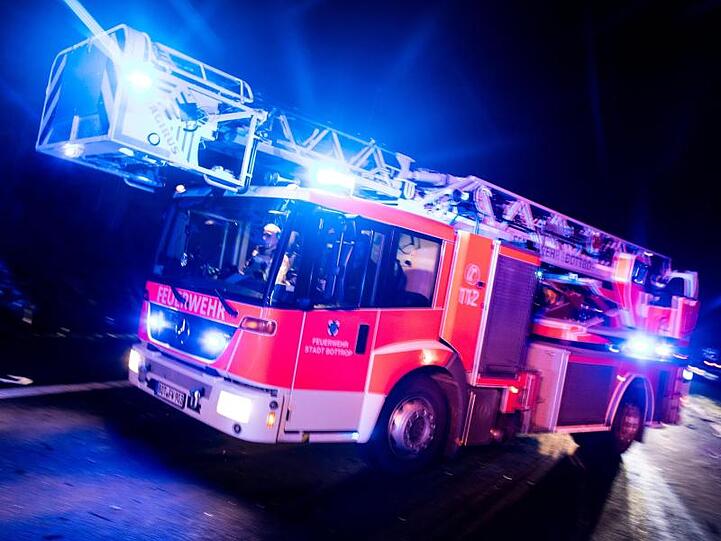 Ein Drehleiterwagen der Feuerwehr fährt mit Blaulicht an einer Unfallstelle vorbei. Foto: Marcel Kusch/dpa/Illustration