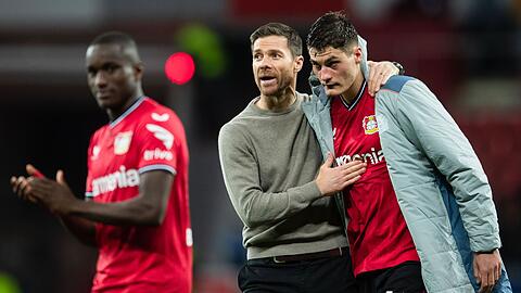 Bayer-Trainer Xabi Alonso (M.) nimmt nach der Partie Patrik Schick (r) in den Arm. Daneben klatscht Moussa Diaby.