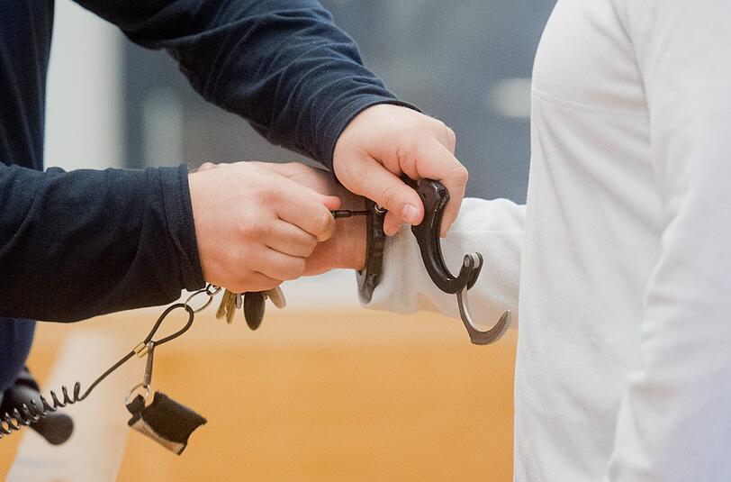 Ein Justizbeamter nimmt dem Angeklagten im Landgericht in Hannover Handschellen ab. Foto: Julian Stratenschulte