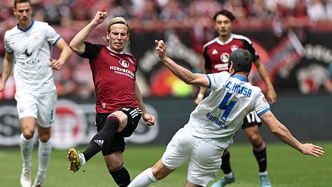 Der Nürnberger Lino Tempelmann (M) kämpft mit Damian Roßbach (r) von Hansa Rostock um den Ball.