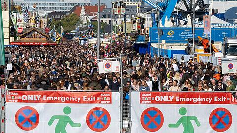 Besucherinnen und Besucher drängen sich hinter Notausgängen durch die Gassen des Oktoberfests.