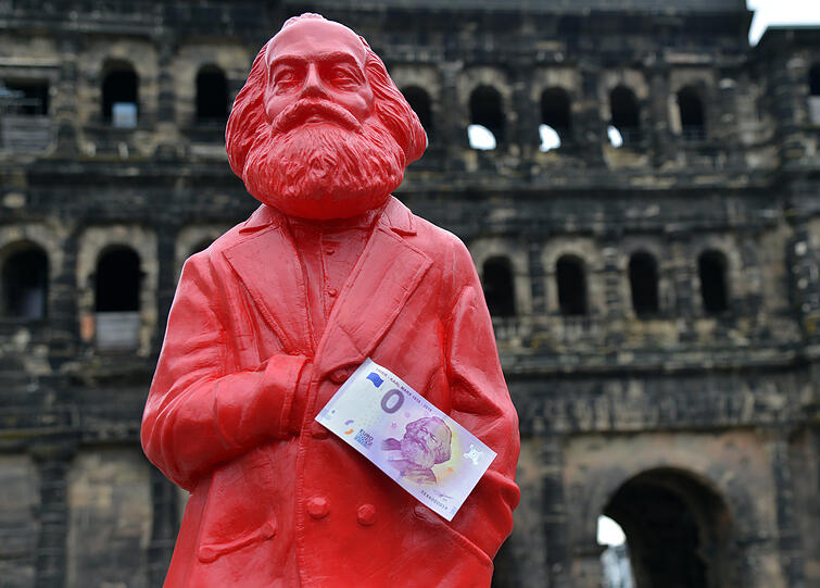 Ein Null-Euro-Schein, den die Trier Tourismus und Marketing GmbH herausgebracht hat, pappt an einer Karl-Marx-Figur des K&uuml;nstlers Ottmar H&ouml;rl. Der zum 200. Geburtstag von Karl Marx vor rund einem Jahr aufgelegte Null-Euro-Schein ist weiterhin ein Verkaufshit.