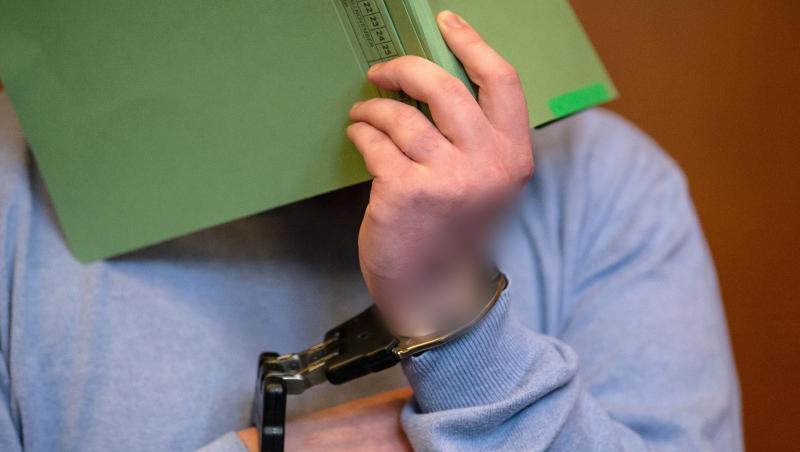 Der Angeklagte sitzt mit einem Aktendeckel vor dem Gesicht auf der Anklagebank im Gerichtssaal. Foto: Swen Pförtner Der Angeklagte sitzt mit einem Aktendeckel vor dem Gesicht auf der Anklagebank im Gerichtssaal. Foto: Swen Pförtner