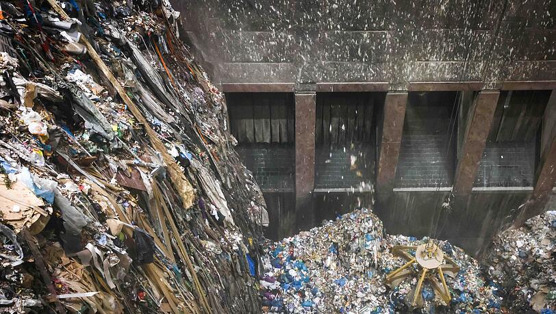 Mit einem großen Greifer sortiert und lockert ein Kran den angelieferten Abfall im Müllbunker einer Müllverwertungsanlage.