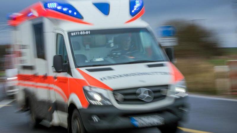 Ein Rettungswagen mit Blaulicht fährt über eine Straße.