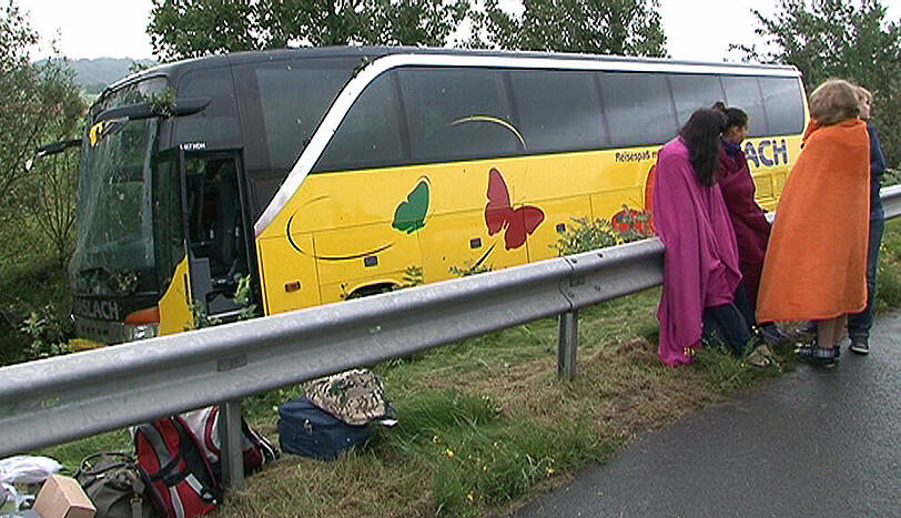Kinder stehen am Sonntag bei Cuxhaven auf der Autobahn 27 (A27) neben einem Reisebus, der nach einem Unfall neben der Fahrbahn steht.