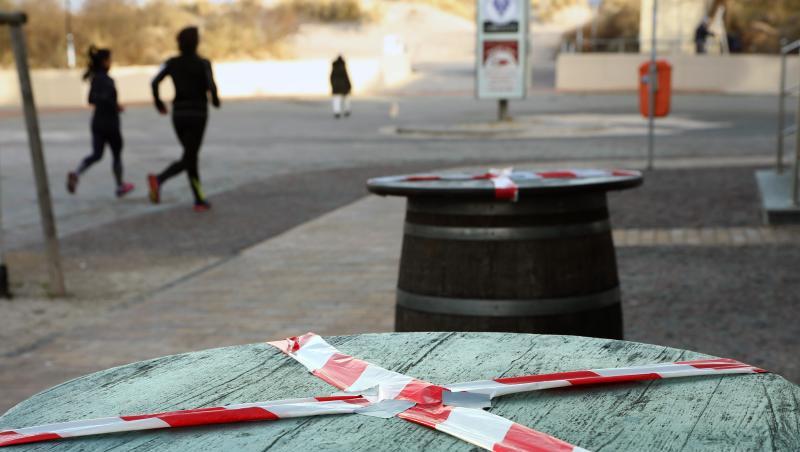Kein gemütliches Beisammensein: Mit einem rot-weißen-Flatterband sind Stehtische an der Promenade des Ostseebades Warnemünde abgeklebt.