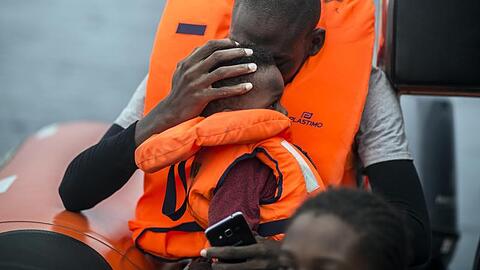 Ein Mann hält seinen Sohn im Arm, nachdem er gemeinsam mit anderen Flüchtlingen gerettet wurde.