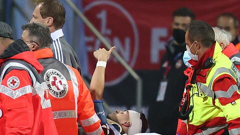 Der Nürnberger Tom Krauß (M) wird verletzt aus dem Stadion getragen, zeigt aber mit dem Daumen nach oben.