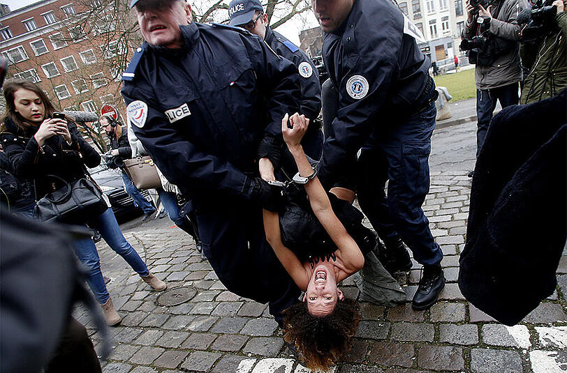 Eine Femen-Aktivistin wird von der Polizei festgenommen. Sie ist zuvor auf das Auto von Strauss-Kahn gestiegen.