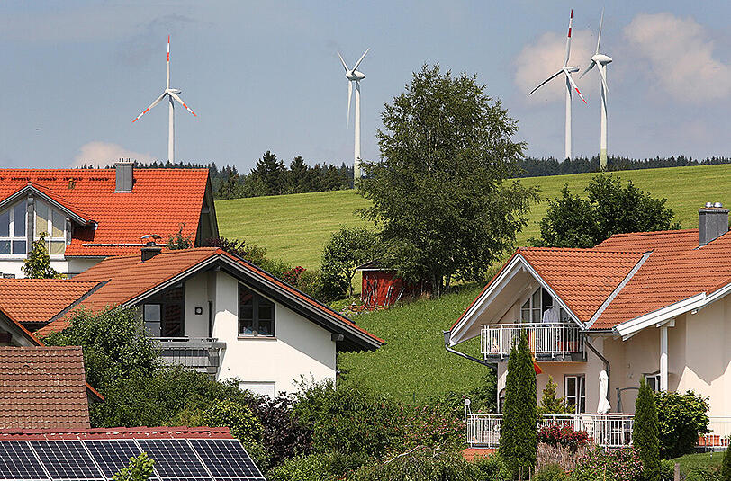 Windräder stehen hinter einer Neubausiedlung. Foto: Karl-Josef Hildenbrand/Archiv