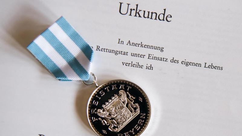 Die "Bayerische Rettungsmedaille" und die dazugehörigen Urkunde liegen während einer Verleihung zusammen. Foto: Peter Kneffel/Archivbild Die "Bayerische Rettungsmedaille" und die dazugehörigen Urkunde liegen während einer Verleihung zusammen. Foto: Peter Kneffel/Archivbild