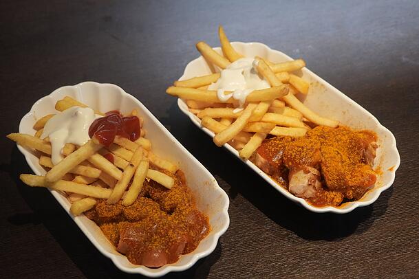 Links die vegane Currywurst und rechts die mit Kalbsbratwurst. Die Soße schmeckt auf beiden Varianten gut.