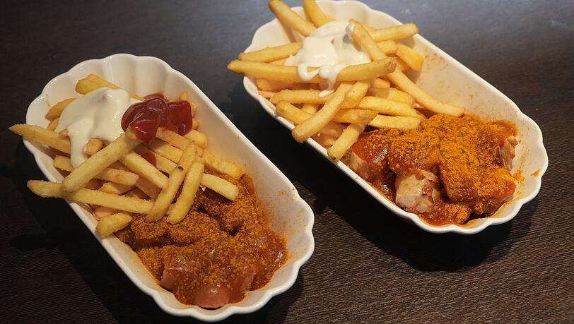 Links die vegane Currywurst und rechts die mit Kalbsbratwurst. Die Soße schmeckt auf beiden Varianten gut.