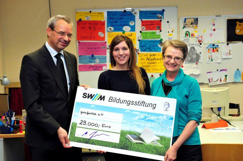 Martin Janke, Geschäftsführer der SWM Bildungsstiftung, übergibt den Förderscheck an Michaela Kleber, Geschäftsführerin von pro familia München, und die für das Projekt verantwortliche Pädagogin Lisa Geiger.