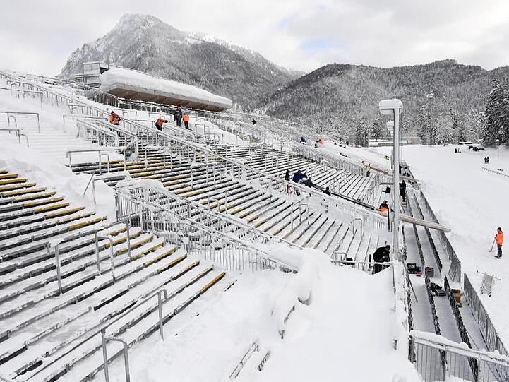 Helfer befreien die Zuschauertribühne in der Chiemgau-Arena in Ruhpolding von den Schneemassen.