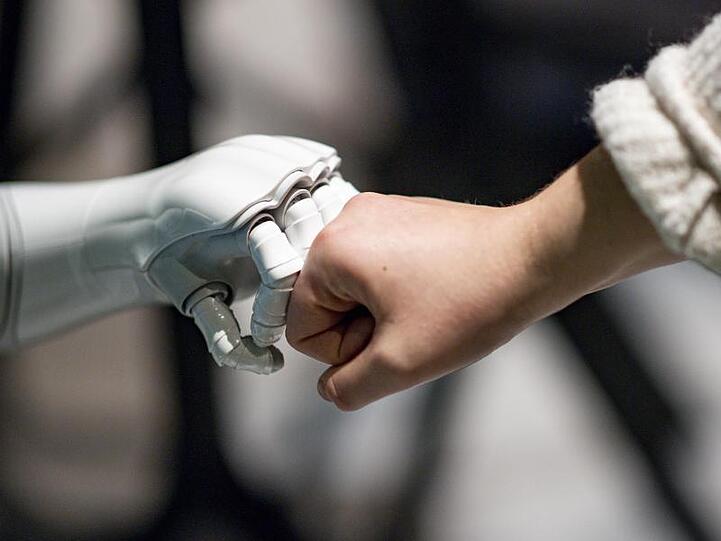 Ein Roboter interagiert mit einer Frau. Foto: Axel Heimken/dpa/Archivbild