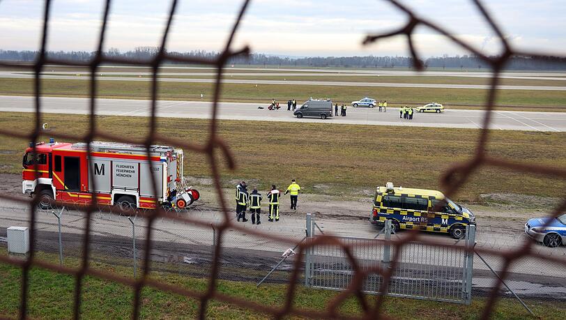 Klimaaktivisten sitzen mit angeklebten Händen auf dem Zubringer einer Landebahn am Münchner Airport.