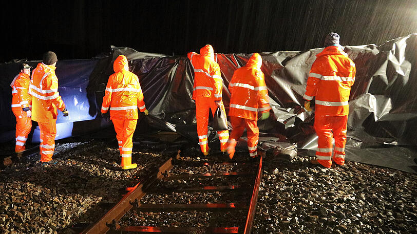 Arbeiter sichern Bahngleise bei Immenstadt mit einem Hochwasserwall.