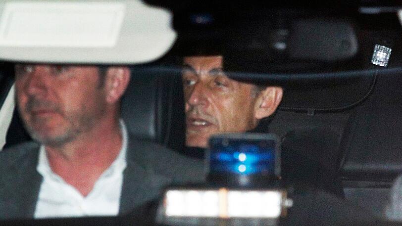 Nicolas Sarkozy (r), damaliger Staatspräsident von Frankreich, verlässt in einem Auto eine Außenstelle des französischen Innenministeriums. Nach zweitägigen Befragungen zu möglichen Wahlkampfspenden aus Libyen hat die französische Justiz ein Verfahren gegen den früheren Staatspräsidenten Nicolas Sarkozy eröffnet.