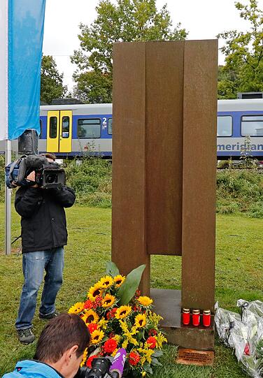 Ein Meridian-Zug fährt am 07.10.2016 während der Einweihung eines Mahnmals für die Opfer des Zugunglücks in Bad Aibling (Bayern) hinter einer Stele aus Stahl vorbei. Die rund drei Meter hohe Skulptur des Künstlers Franz Ferdinand Wörle erinnert unweit der Unfallstelle an das Zugunglück mit 12 Toten.