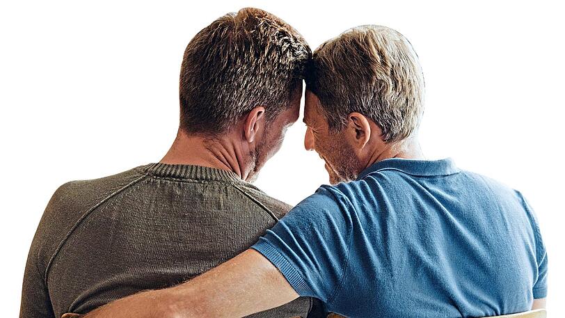 Zwei Männer stecken lachend die Köpfe zusammen.