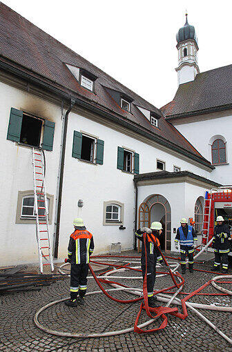Einsatzkräfte der Feuerwehr stehen am Sonntagmorgen vor dem Franziskanerkloster in Füssen.