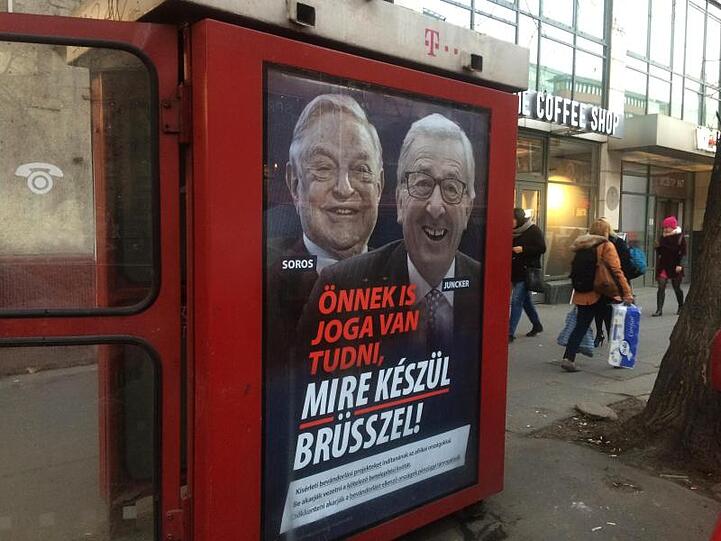 An einer Telefonzelle in Budapest hängt ein Plakat mit den Konterfeis von George Soros und Jean-Claude Juncker mit der Unterschrift "Sie haben ein Recht darauf zu wissen, was Brüssel vorhat".