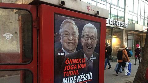 An einer Telefonzelle in Budapest hängt ein Plakat mit den Konterfeis von George Soros und Jean-Claude Juncker mit der Unterschrift "Sie haben ein Recht darauf zu wissen, was Brüssel vorhat".