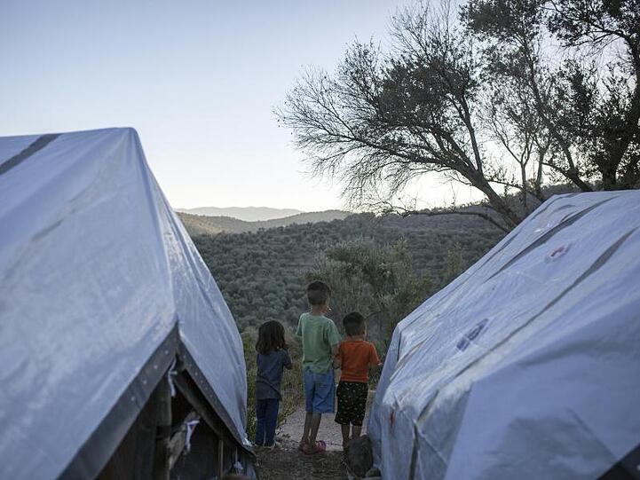 Kinder stehen zwischen Zelten in einem provisorischen Flüchtlingslager auf Lesbos.