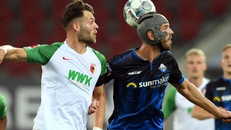 Klaus Gjasula (r) von Paderborn und Edward Löwen von Augsburg im Kopfballduell. Foto: Matthias Hangst/Getty Images Europe/Pool/dpa Klaus Gjasula (r) von Paderborn und Edward Löwen von Augsburg im Kopfballduell. Foto: Matthias Hangst/Getty Images Europe/Pool/dpa