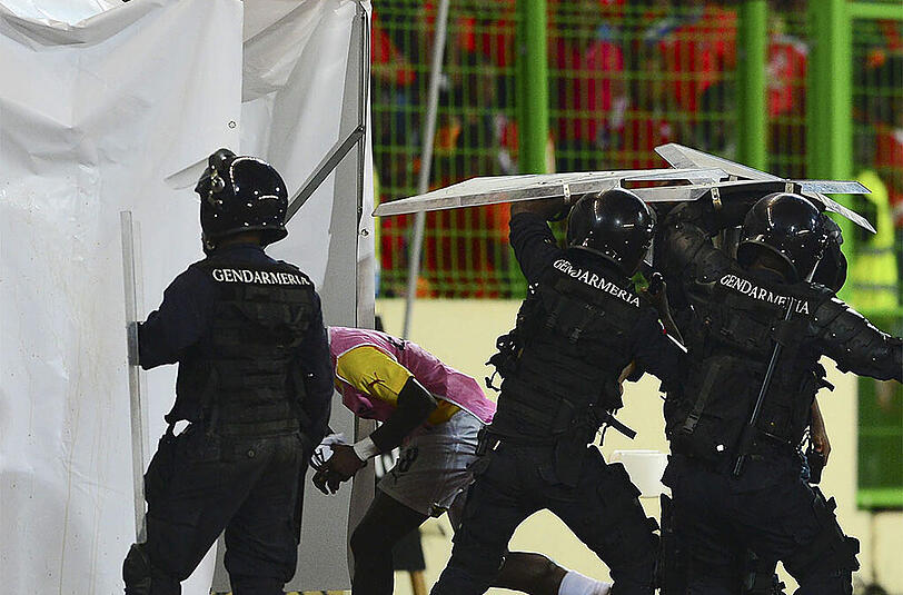 Polizisten und Sicherheitskräfte bringen die Spieler im Inneren des Stadions in Sicherheit.