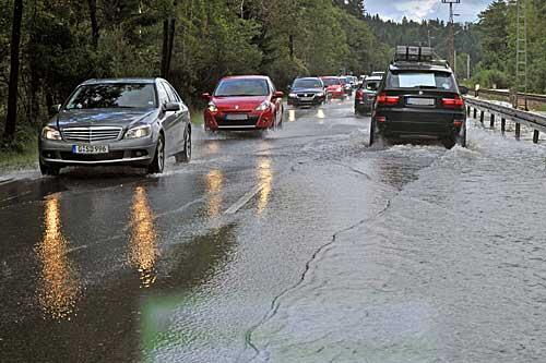 Auch das gehört zum Somnmer 2010: Autos auf einer überfluteten Straßen bei Garmisch-Partenkirchen. Anhaltender Regen hatte die Straße vom nahen Bach her überspült.