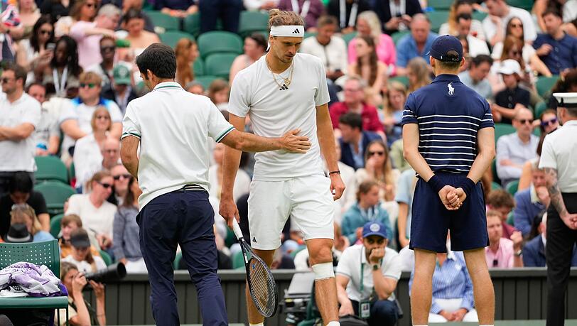 Alexander Zverev (r) geht zurück auf den Platz, nachdem ihm nach seinem Sturz ein Verband um sein Knie gewickelt worden ist.