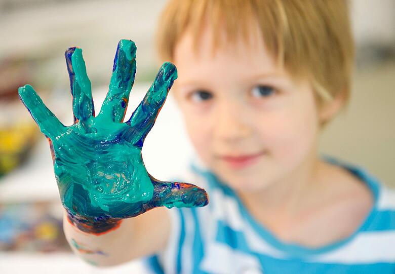 Der dreijährige Paul zeigt am Donnerstag im Kinderkunsthaus in München seine mit Farbe verschmierte Hand in die Kamera des Fotografen, mit der er gerade ein Bild gemalt hat.