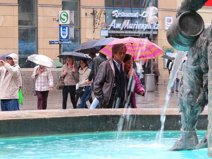 Regenschirm auf und los geht's zum Sightseeing: Touristen am Marienplatz