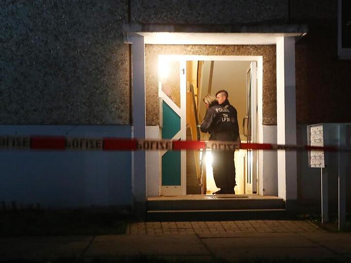 Polizeibeamte stehen im Eingang eines Wohnhaus. Hier wurden vier Leichen gefunden.