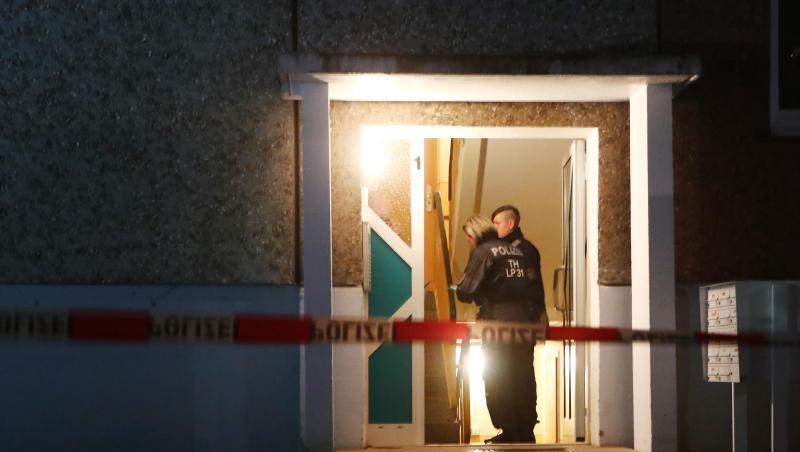 Polizeibeamte stehen im Eingang eines Wohnhaus. Hier wurden vier Leichen gefunden.