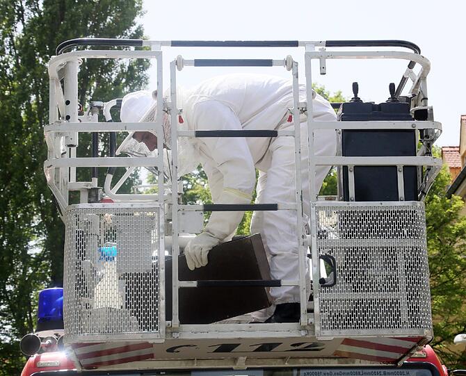 Ein Feuerwehrmann steigt auf die Hebebühne - im Imker-Dress.
