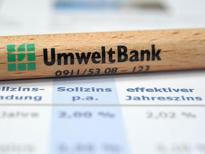 Ein hölzerner Kugelschreiber mit dem Logo der UmweltBank AG liegt auf einem Ausdruck. Foto: David Ebener/Archivbild