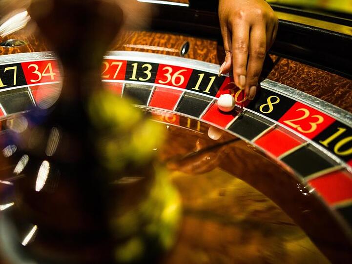Eine Mitarbeiterin einer Spielbank greift beim Roulette nach einer Kugel. Foto: Christoph Schmidt/dpa/Archivbild