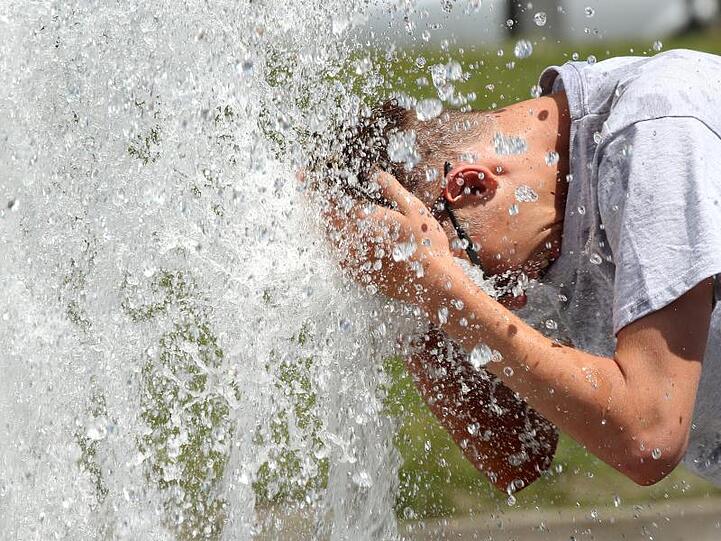 Ein Mann erfrischt sich am Wasser eines Brunnens. Foto: Wolfgang Kumm/Archivbild