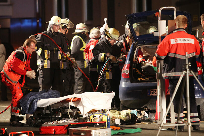 Der Rettungsdienstler (links im Foto) wartet vor der Trage, dass die Feuerwehrmänner die Frau aus dem Auto befreien.