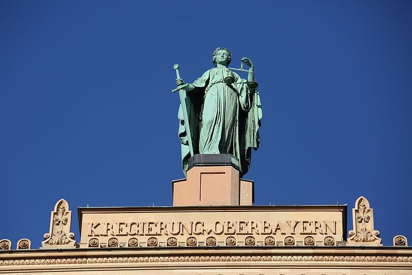 Hoch über der Maximilianstraße thront die Justitia von 1897 auf dem Dach der Regierung von Oberbayern.