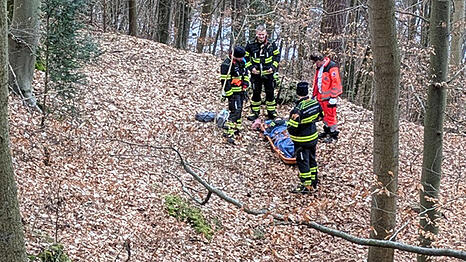 Die Helfer bergen die verketzte Frau an dem steilen Hang im Wald bei Harlaching.