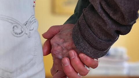 Eine Pflegedienstleiterin führt eine Bewohnerin der Demenz-Wohngemeinschaft an der Hand. Foto: Karl-Josef Hildenbrand/dpa/Archivbild
