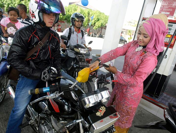 Tanken mal anders! In Indonesien wird einem der Tank von einer Angestellten im traditiollen "Kebaya" befüllt.
