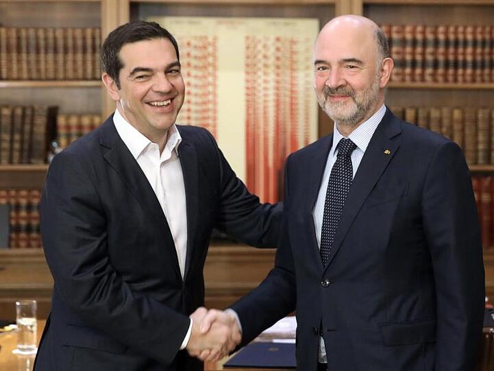 Alexis Tsipras (l), Premierminister von Griechenland, reicht Pierre Moscovici, EU-Kommissar für Wirtschaft und Finanzen, bei einem Treffen zur Begrüßung die Hand.
