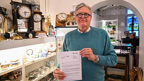 Antiquitätenhändler Florian Mühlbauer in seinem Laden in der Türkenstraße. Er hält seine Kontokündigung in die Kamera. Mühlbauer weiß bis heute nicht, warum das nötig gewesen ist. Die Postbank nennt keine Gründe.